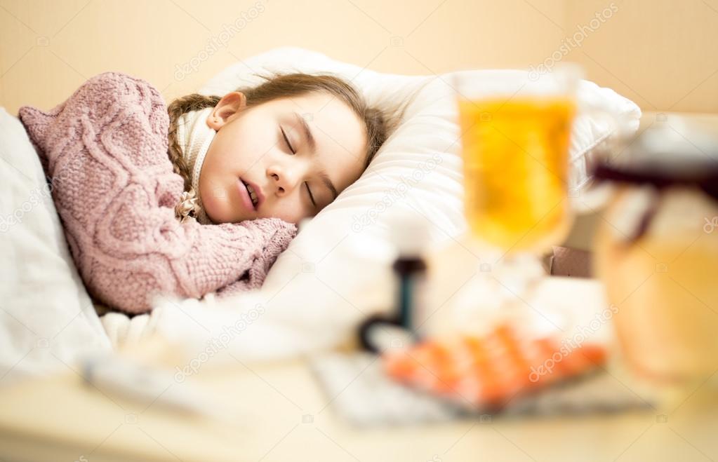 little sick girl in sweater sleeping in bed