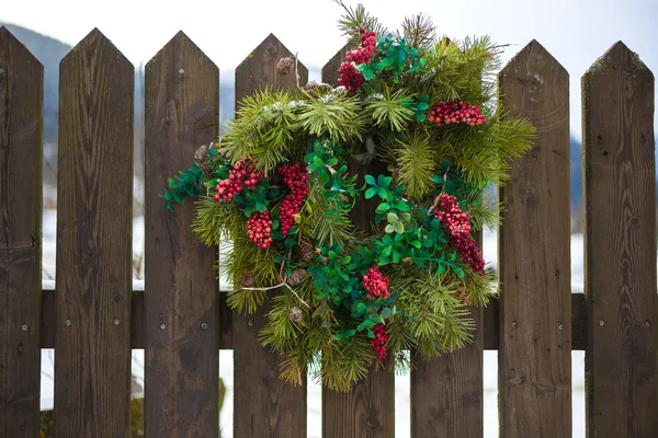 Ahşap çit asılı kırmızı meyveler ile Noel çelenk — Stok fotoğraf