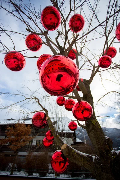 Closeup shot of tree on street decorated with big red balls