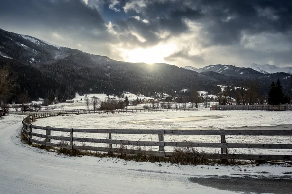 Boerderij met houten hek op highland Oostenrijkse stad bij zonsondergang — Stockfoto