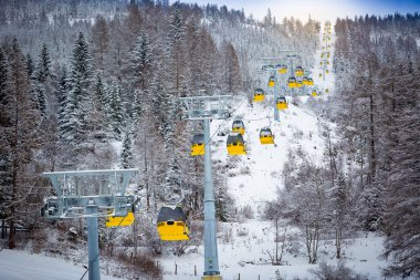 panoramic shot of long line of cable cars on ski slope clipart