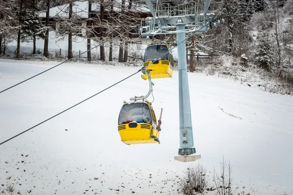 在奥地利阿尔卑斯山的滑雪坡上的黄色电缆车。 — 图库照片