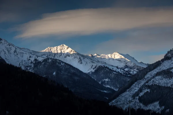 landscape of sun shining on mountain top covered by snow