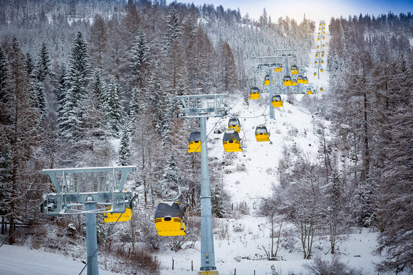 panoramic shot of long line of cable cars on ski slope