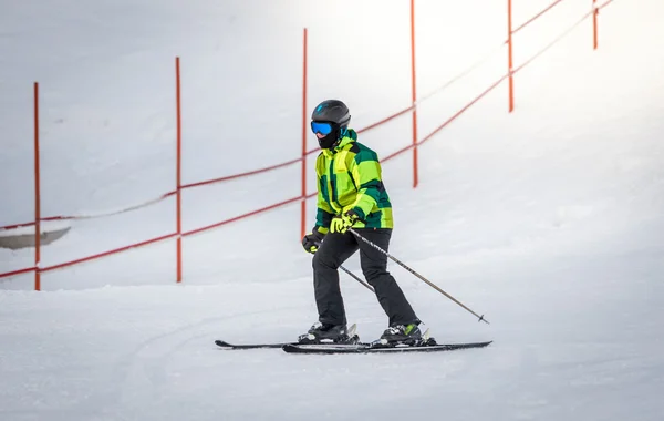 Mann im grünen Anzug beim Skifahren den Berg hinunter — Stockfoto