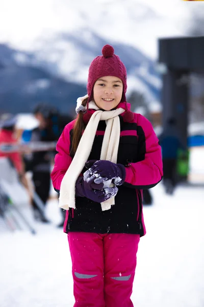 Smiling girl in pink ski suit posing against high mountain cover — Stock Photo, Image