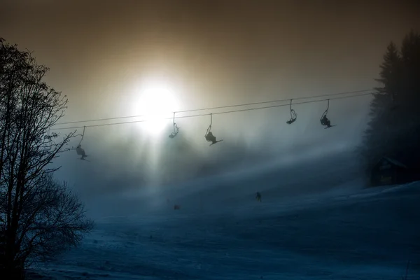 Silhouette foto di impianti di risalita scattata contro il sole splendente in mountai — Foto Stock