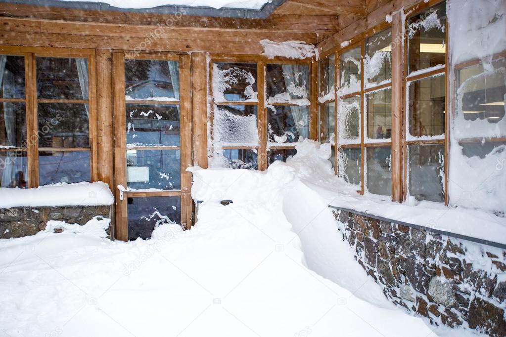 Austrian wooden house with big windows covered by snow at snowst