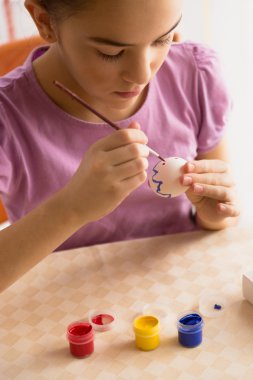 Closeup shot of girl painting pattern on Easter egg
