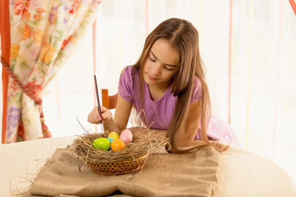 Linda chica decorando huevos de Pascua en la cesta —  Fotos de Stock