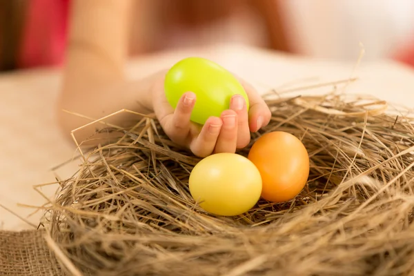 Closeup shot of young girl taking green Easter egg from the nest — Stock Photo, Image