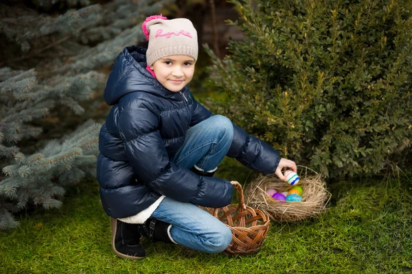 Meisje vinden Pasen eieren op gazon op achtertuin — Stockfoto