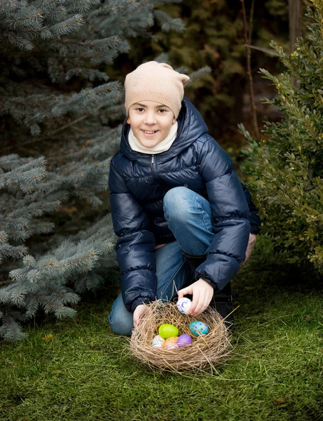 Ragazza sorridente che raccoglie uova di Pasqua in cortile — Foto Stock