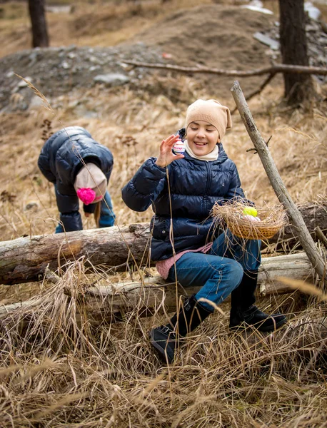 Roztomilé dívky mají velikonoční vajíčko lov v lese na chladný den dubna — Stock fotografie