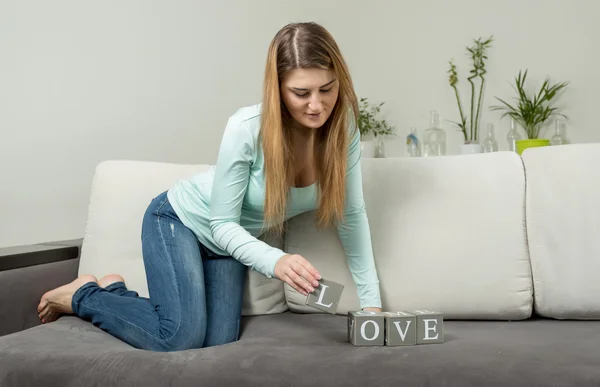 Kvinnan gör ordet "kärlek" från tegelstenar med bokstäver — Stockfoto