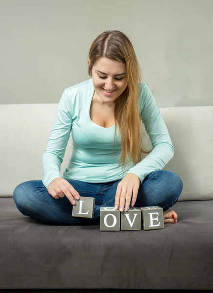 Жінка будує слово "любов" з декоративних цеглин — стокове фото