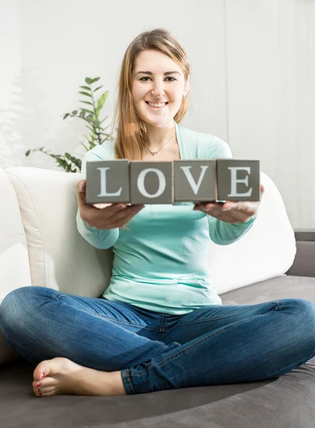 Foto konseptual wanita memegang kata "cinta" yang terbuat dari batu bata — Stok Foto