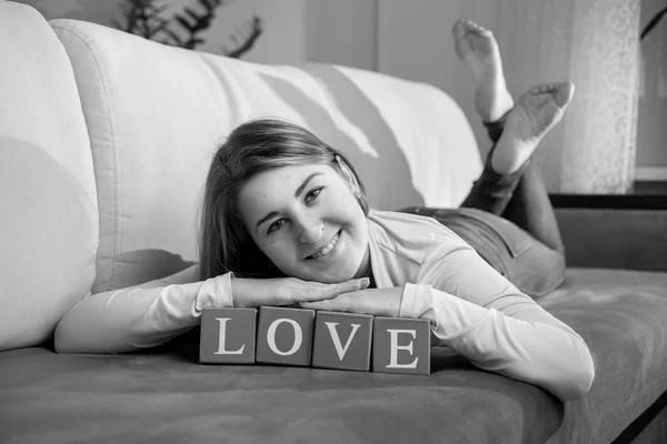 Monochrome portrait of happy woman lying on couch with word "lov — Stock Photo, Image