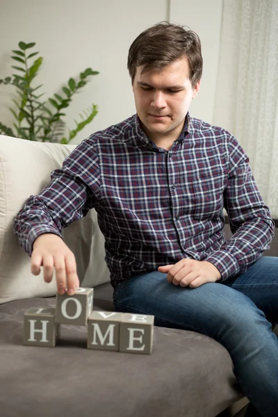 Junger Mann bastelt Wort "Heimat" aus Buchstaben auf Würfeln — Stockfoto