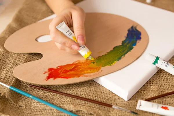 Gros plan de l'artiste pressant la peinture à l'huile sur palette à partir du tube — Photo