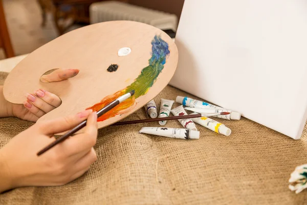 Caucasian woman holding wooden pallet with paints — Stock Photo, Image