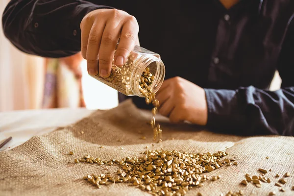 Bergmann sitzt am Tisch und schüttet Gold aus Glas — Stockfoto