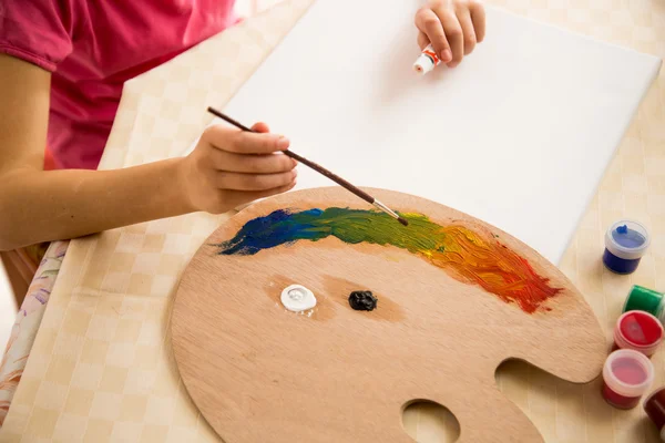 Niña sosteniendo paleta y dibujo sobre lienzo usando pinturas al óleo — Foto de Stock