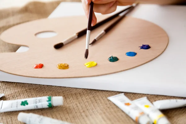 Woman holding paintbrush and choosing color on the pallet — Stock Photo, Image