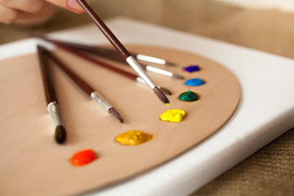 Professional paintbrushes lying on pallet dipped in oil paint — Stock Photo, Image