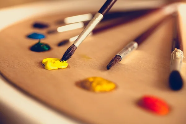 Foto tonificada de pinceles tumbados en la paleta sumergidos en pintura al óleo — Foto de Stock