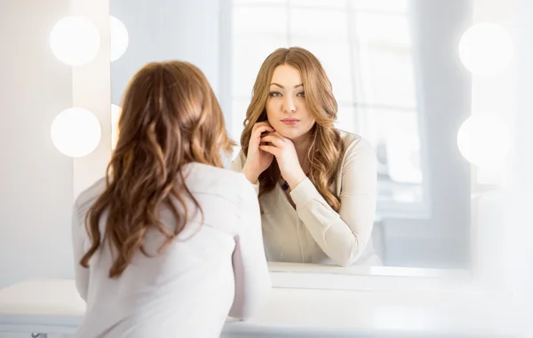 Mujer elegante con el pelo rizado mirando el reflejo en el espejo —  Fotos de Stock