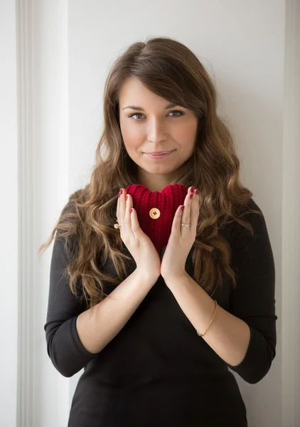 Portrait of smiling woman holding red knitted heart — Stock Photo, Image