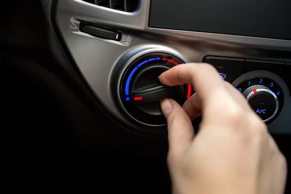 Closeup shot of young woman turning car air conditioner switch — Stock Photo, Image