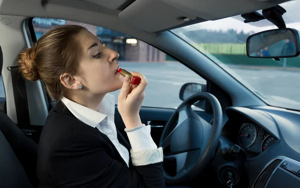 Geschäftsfrau trägt während des Autofahrens Kosmetika auf — Stockfoto