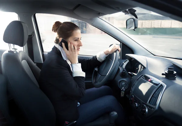 Сконцентрированная женщина разговаривает по телефону и за рулем автомобиля — стоковое фото