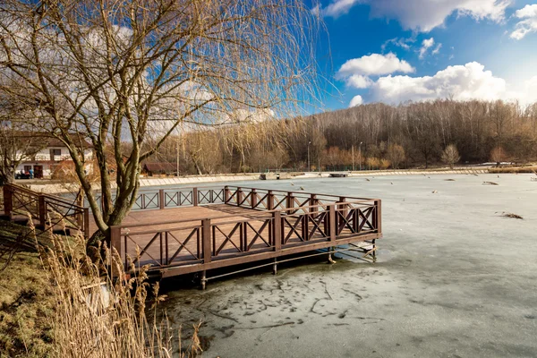 Drewniane molo nad jeziorem pokryte lodem w słoneczny dzień — Zdjęcie stockowe