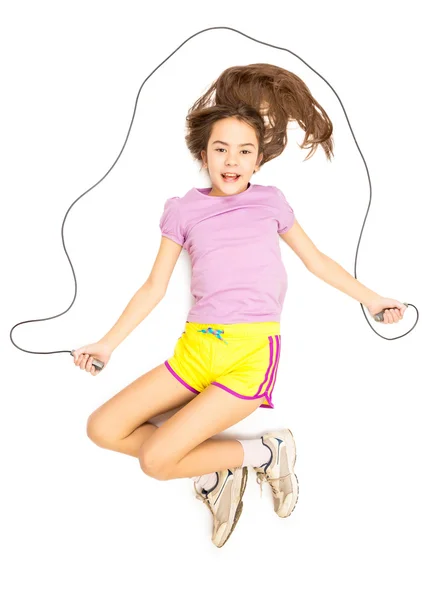 床の上に横たわるとロープでスキップするふりをして笑みを浮かべて少女 — ストック写真