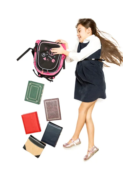 Isolierte Aufnahme eines süßen Schulmädchens, das einen Rucksack voller Bücher leert — Stockfoto