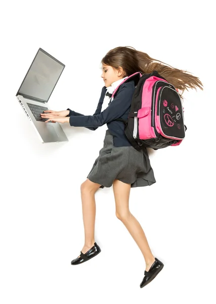 Colegial bonito com mochila usando laptop enquanto caminha — Fotografia de Stock