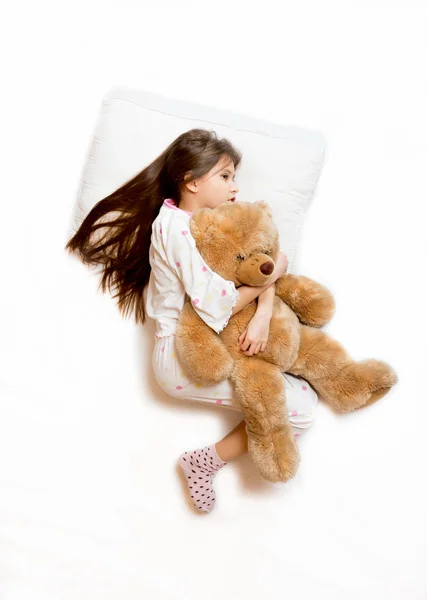 Aislado disparo de linda chica acostada en la cama y abrazando oso de peluche —  Fotos de Stock