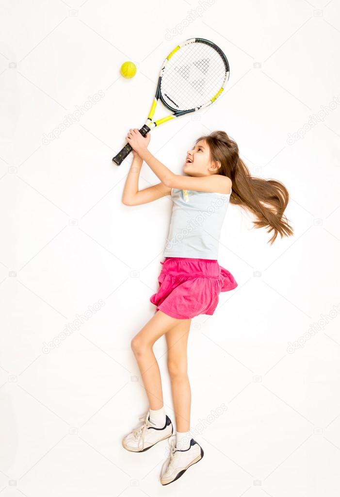 happy girl lying on floor and hitting tennis ball with racket