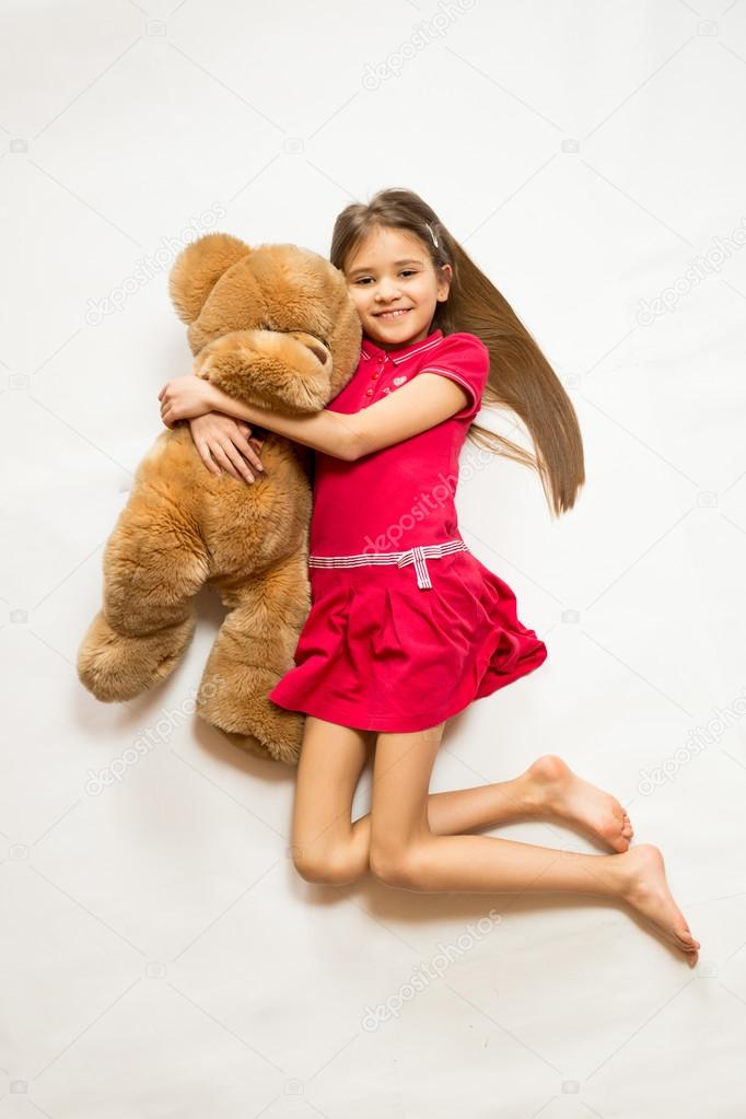 Isolated shot of cute smiling girl holing big brown teddy bear