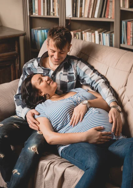 Mutlu gülümseyen hamile çift kanepe oturma odasında yatan — Stok fotoğraf