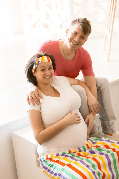 Šťastný pár těhotná objímání a při pohledu na fotoaparát — Stock fotografie
