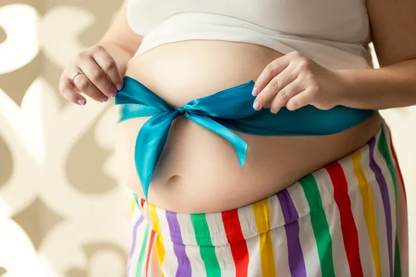 Toned photo of young pregnant woman holding bow on tummy — Stock Photo, Image