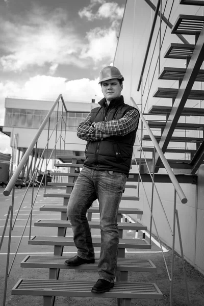 Schwarz-Weiß-Aufnahme eines jungen männlichen Architekten, der auf einer Treppe steht — Stockfoto