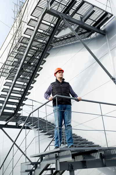 Construction worker standing on steel staircase at factory — Stock Photo, Image
