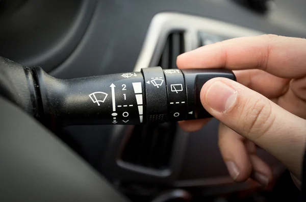 Male driver adjusting speed of screen wipers in car — Stock Photo, Image