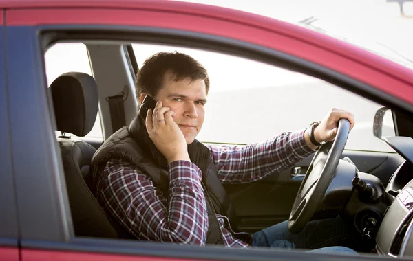 Portrait of male driver talking by phone while driving a car — Stock Photo, Image