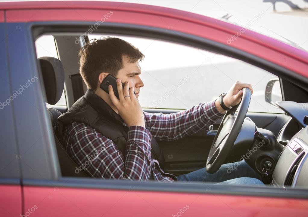 young man talking by phone while driving a car